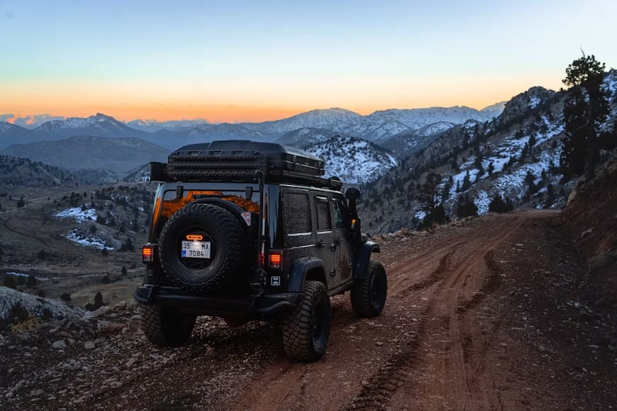 A 4x4 on a mountain dirt road, set up for overlanding