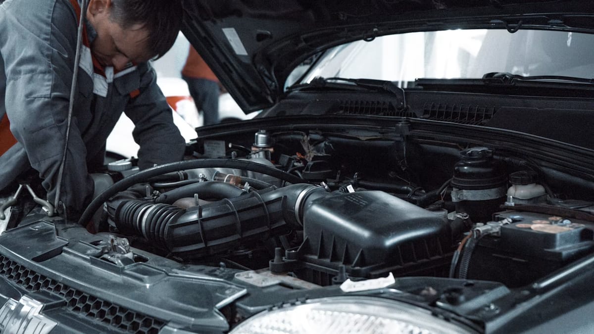 A mechanic inspecting a used car engine before purchase